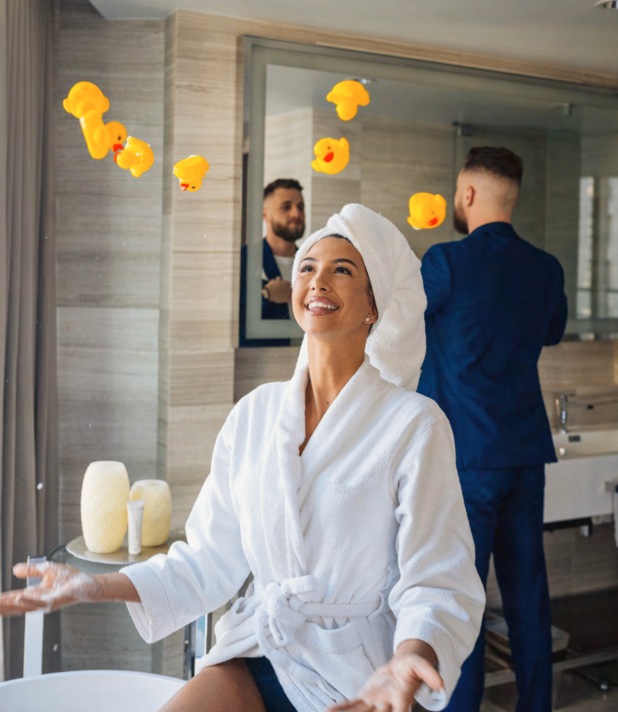 Paradox lifestyle photo of a guest in a robe with floating rubber ducks in a hotel bathroom.