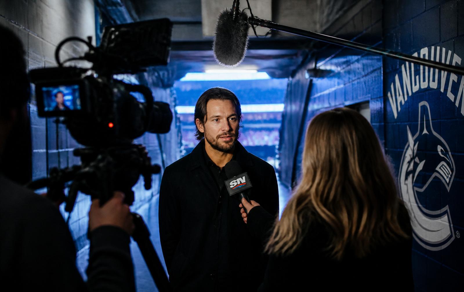 Former Canucks player being interviewed in the arena tunnel for a broadcast piece.
