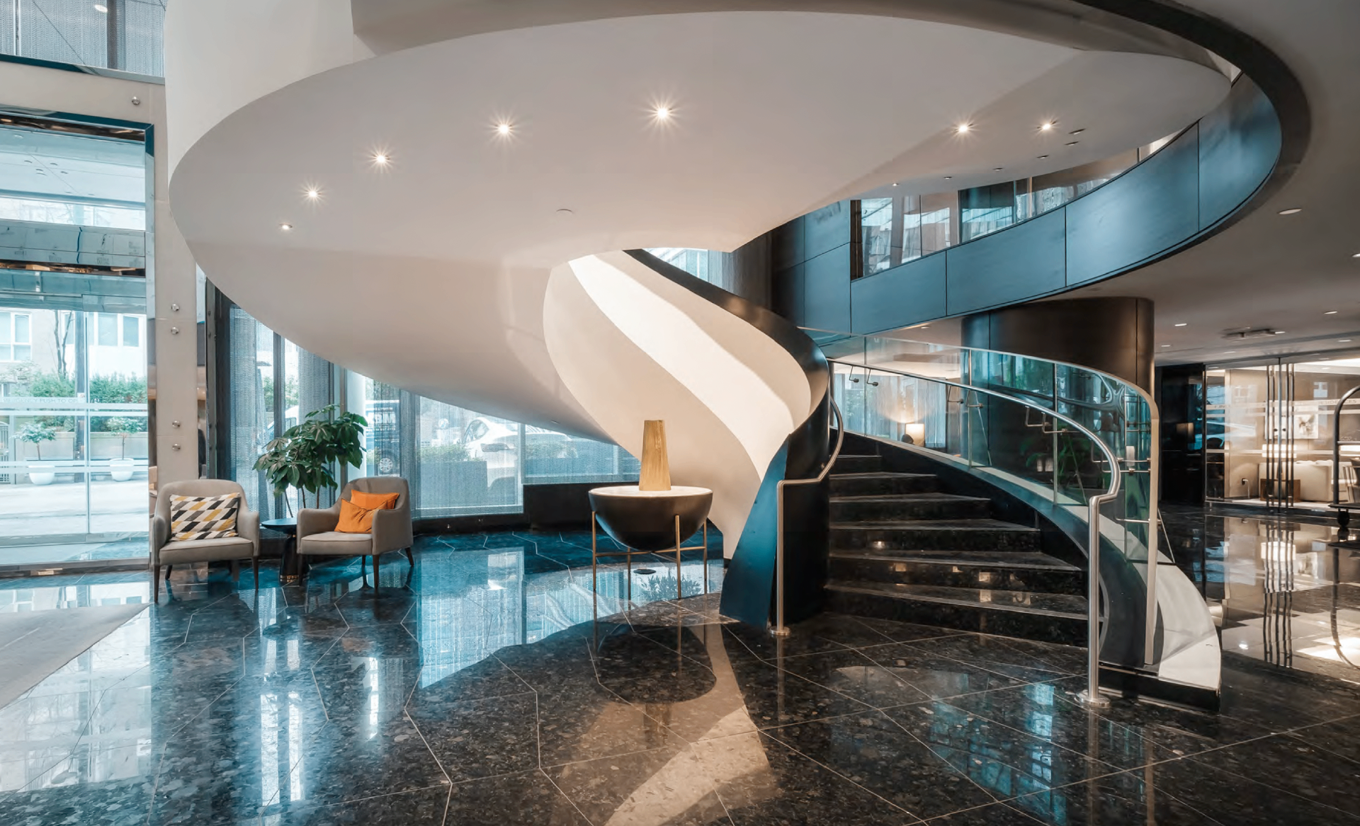 Paradox lobby photograph of a sculptural white spiral staircase over polished marble floors.